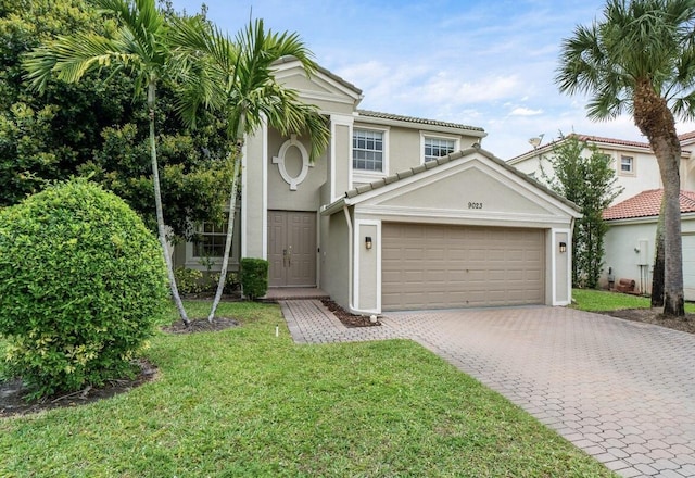 view of front facade with a tile roof, an attached garage, decorative driveway, a front lawn, and stucco siding