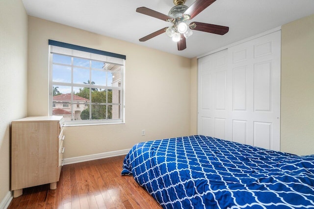 bedroom with a closet, wood-type flooring, a ceiling fan, and baseboards