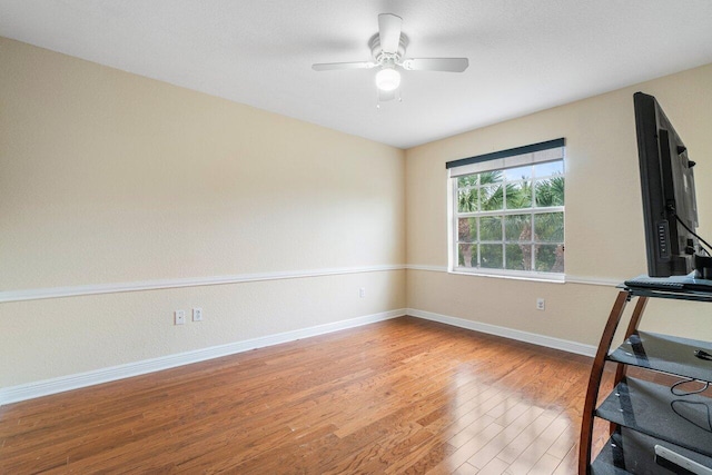 workout area featuring ceiling fan, light wood-style flooring, and baseboards