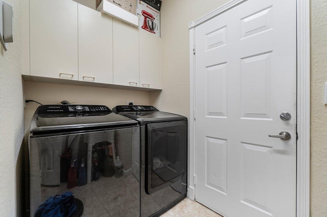 laundry area featuring light tile patterned floors, washing machine and clothes dryer, and cabinet space