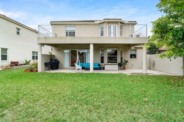 rear view of property with a balcony, an outdoor living space, a lawn, and a patio