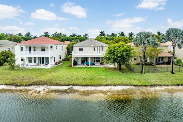 exterior space with a patio, fence private yard, a balcony, a water view, and a yard