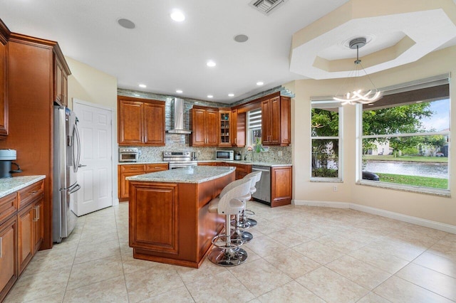 kitchen with stainless steel appliances, visible vents, wall chimney range hood, a center island, and glass insert cabinets