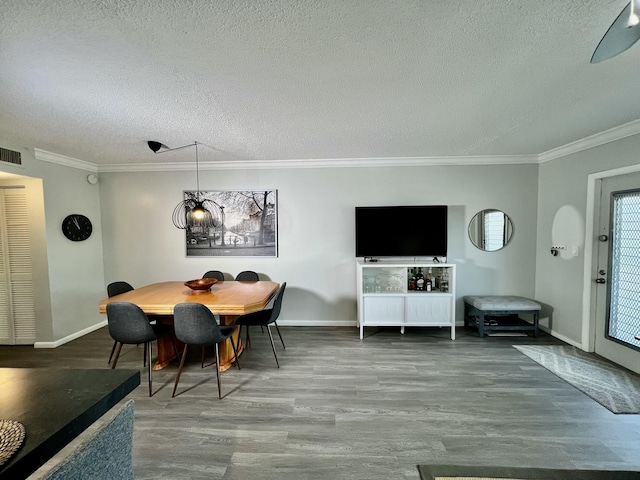 dining space with baseboards, a textured ceiling, wood finished floors, and crown molding