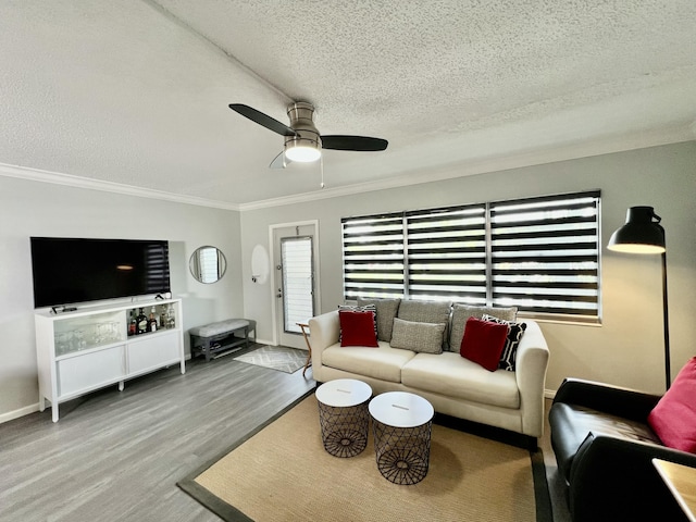 living area featuring ornamental molding, ceiling fan, a textured ceiling, wood finished floors, and baseboards