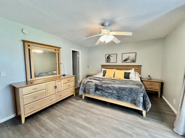 bedroom featuring a ceiling fan, a textured ceiling, baseboards, and wood finished floors