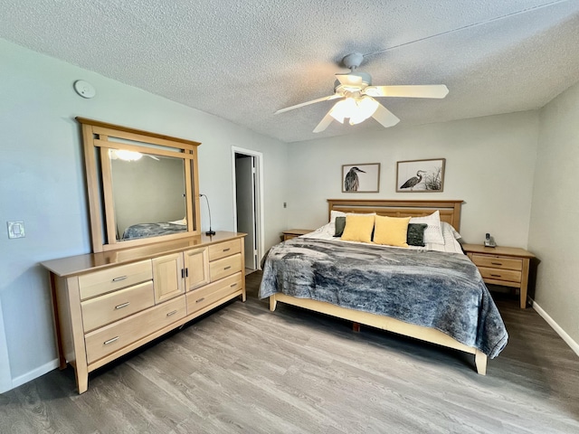 bedroom with a textured ceiling, baseboards, and wood finished floors