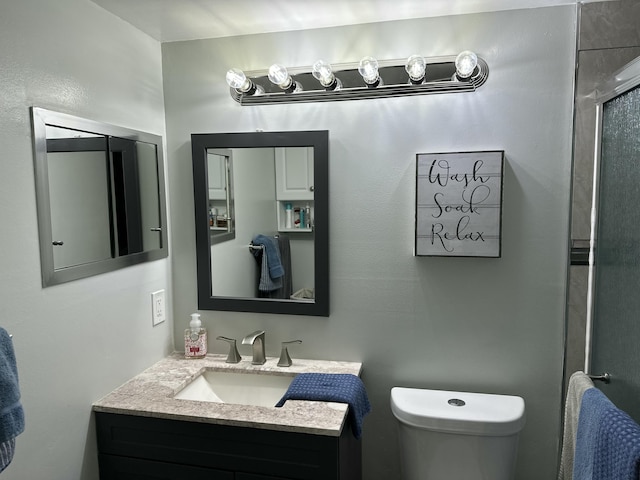 bathroom with toilet, an enclosed shower, and vanity