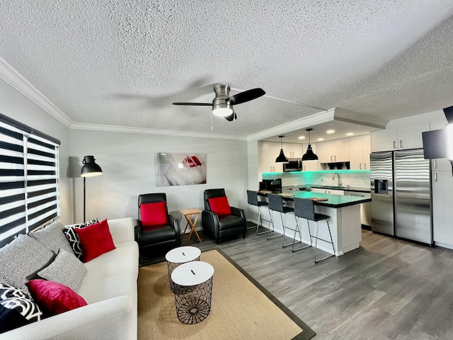 living area with ceiling fan, a textured ceiling, dark wood finished floors, and crown molding