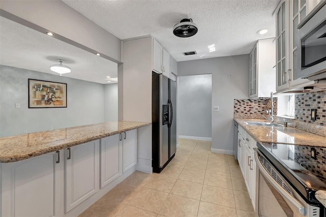 kitchen featuring stainless steel appliances, light stone countertops, glass insert cabinets, and white cabinetry