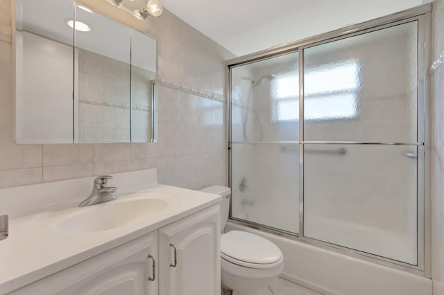 bathroom with decorative backsplash, toilet, enclosed tub / shower combo, vanity, and tile walls