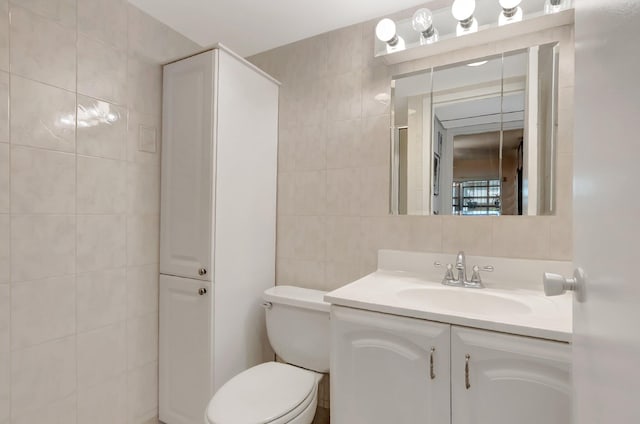 bathroom featuring a closet, tile walls, toilet, and vanity