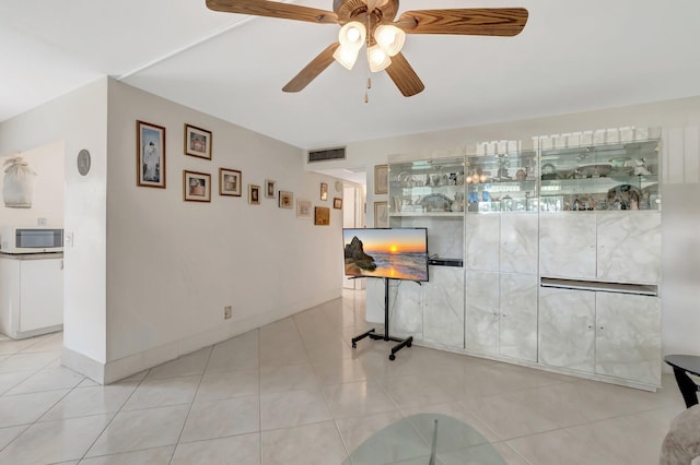 bar with ceiling fan, white microwave, light tile patterned flooring, visible vents, and baseboards