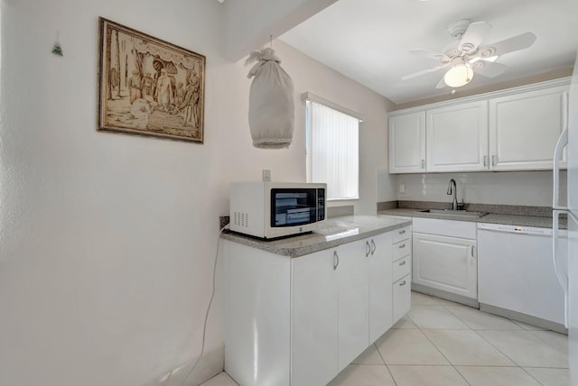 kitchen featuring white dishwasher, white cabinetry, light countertops, and a sink