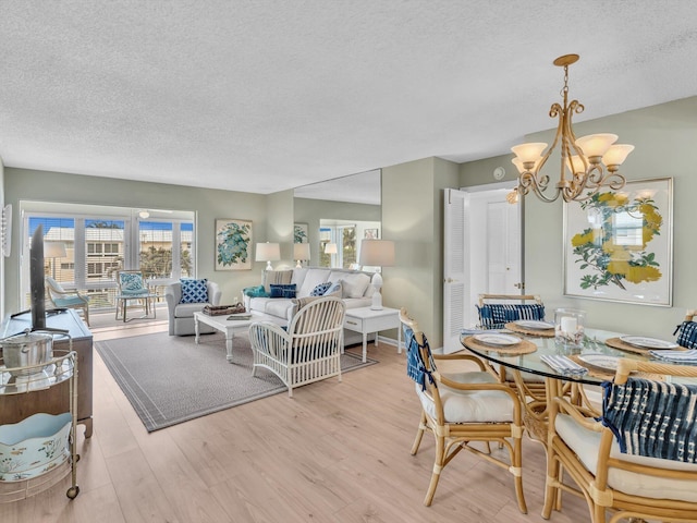 dining room featuring a textured ceiling, light wood finished floors, and a notable chandelier