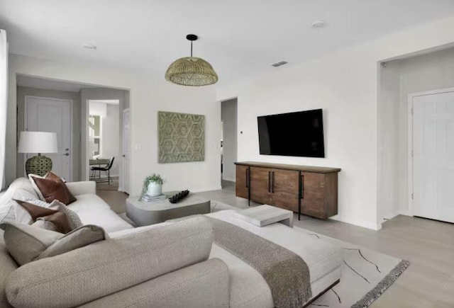 living area with light wood finished floors, visible vents, and baseboards