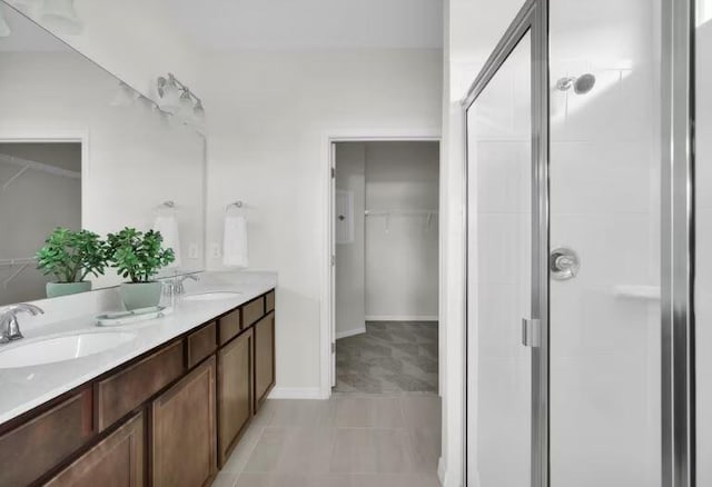 bathroom with double vanity, a shower stall, a spacious closet, and a sink