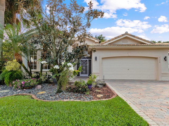 view of front of house featuring an attached garage, a tiled roof, decorative driveway, and stucco siding