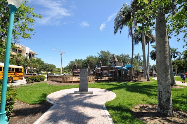 view of home's community featuring playground community, a lawn, and fence