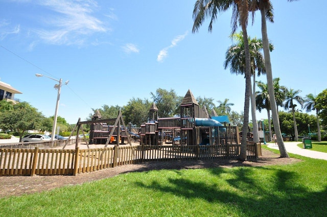 community jungle gym featuring a yard and fence