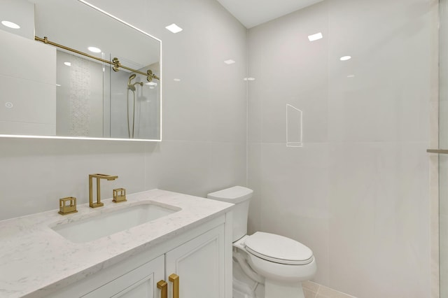 full bath with toilet, vanity, a shower stall, and tile walls