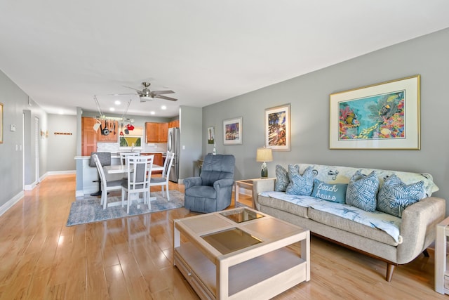 living area with a ceiling fan, recessed lighting, light wood-style flooring, and baseboards