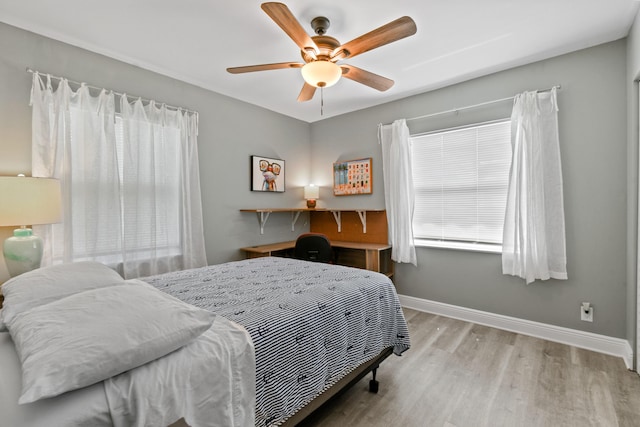 bedroom featuring light wood-type flooring, ceiling fan, multiple windows, and baseboards