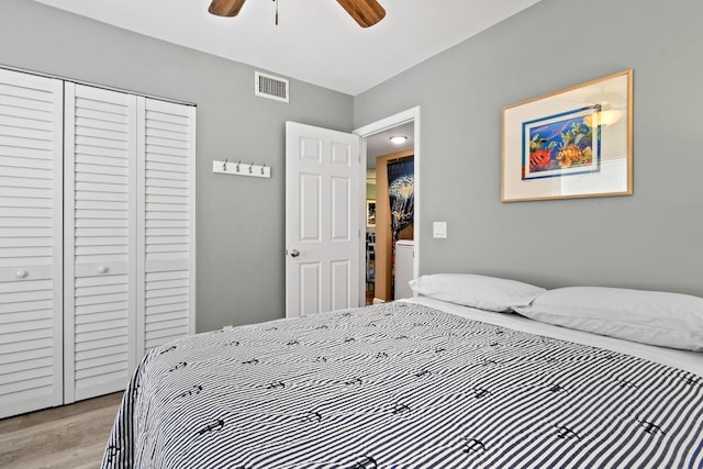 bedroom featuring light wood-style flooring, visible vents, ceiling fan, and a closet