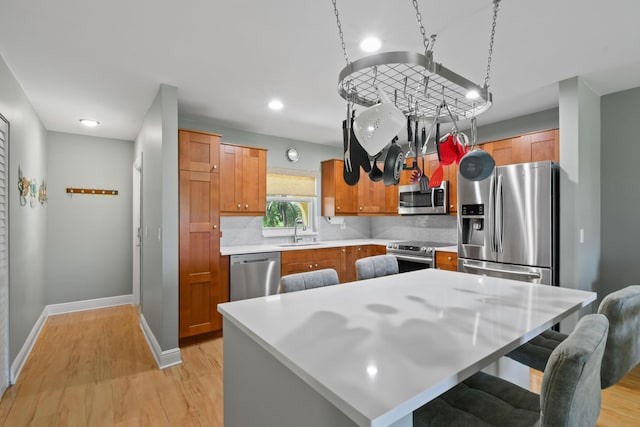 kitchen featuring light countertops, appliances with stainless steel finishes, light wood-type flooring, and a center island