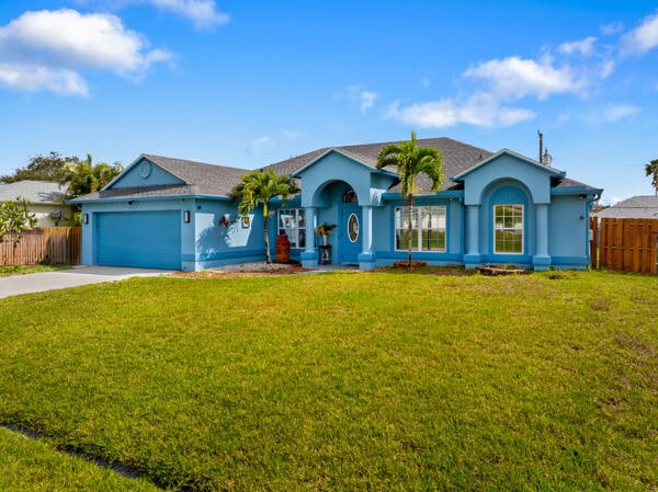 single story home with stucco siding, fence, concrete driveway, a front yard, and a garage