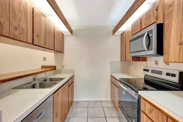 kitchen with light tile patterned floors, tasteful backsplash, light countertops, appliances with stainless steel finishes, and a sink