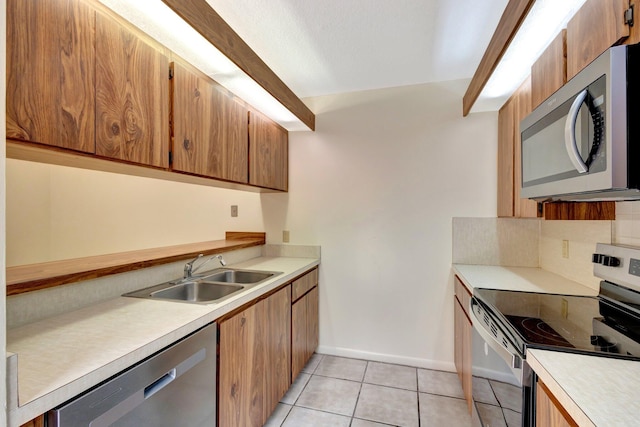 kitchen with light tile patterned floors, stainless steel appliances, light countertops, backsplash, and a sink