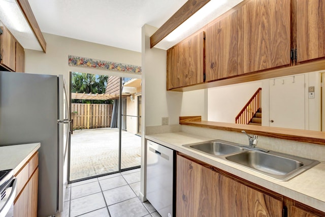 kitchen featuring light tile patterned floors, stainless steel appliances, a sink, and light countertops