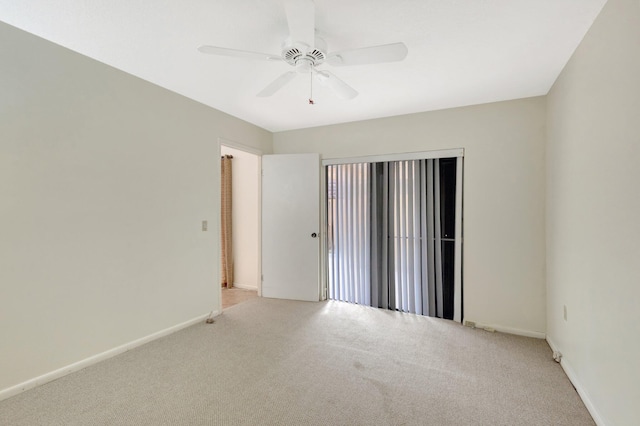 carpeted spare room featuring a ceiling fan and baseboards