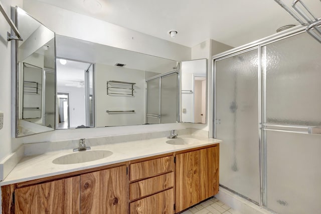 full bathroom featuring double vanity, a stall shower, a sink, and visible vents