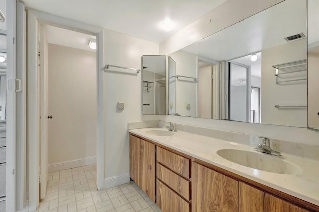 full bath with visible vents, a sink, baseboards, and double vanity