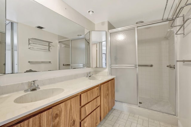 bathroom featuring a stall shower, visible vents, a sink, and double vanity