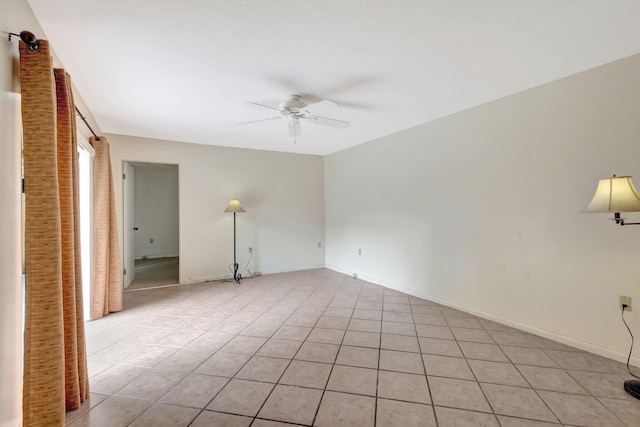 unfurnished room with ceiling fan, light tile patterned floors, and baseboards