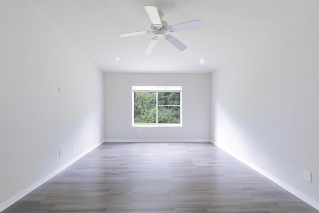 empty room with a ceiling fan, baseboards, and dark wood-type flooring