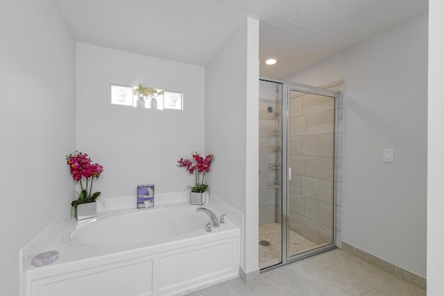 full bathroom featuring a textured ceiling, baseboards, a bath, tile patterned floors, and a stall shower