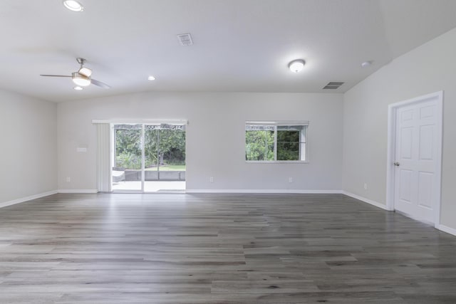 unfurnished room with dark wood-style floors, vaulted ceiling, visible vents, and plenty of natural light