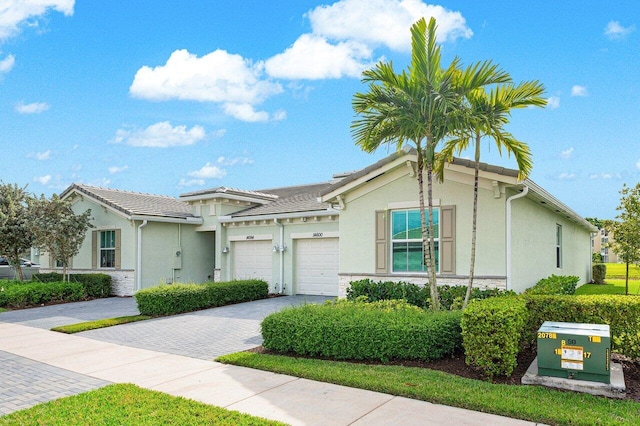 ranch-style home featuring decorative driveway, an attached garage, and stucco siding