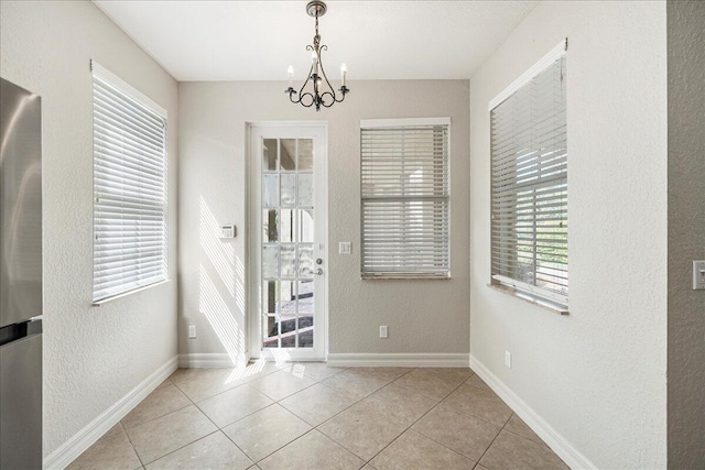 doorway with a textured wall, a notable chandelier, baseboards, and light tile patterned floors