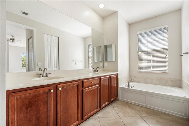 bathroom featuring tile patterned flooring, double vanity, a sink, and a bath