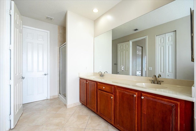 bathroom with double vanity, a sink, visible vents, and a shower stall