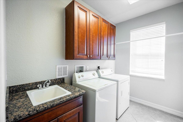 washroom with washing machine and dryer, a sink, visible vents, a wealth of natural light, and cabinet space