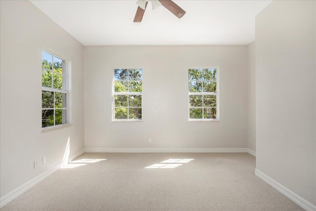 carpeted spare room with plenty of natural light, a ceiling fan, and baseboards