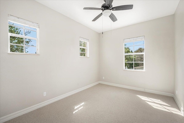 carpeted spare room with a ceiling fan and baseboards