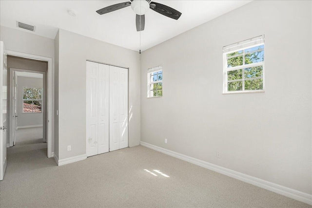 unfurnished bedroom featuring baseboards, a closet, visible vents, and light colored carpet