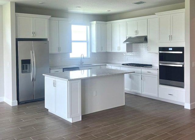 13402 SW Sorella Dr, Port Saint Lucie, FL 34987 - kitchen featuring stainless steel appliances, under cabinet range hood, a sink, a center island, and dark wood-type flooring